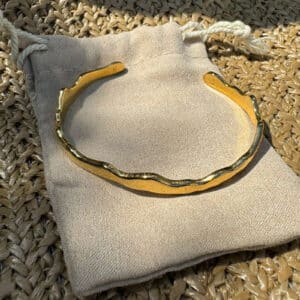 Wellenförmiger goldener Armreif aus Edelstahl mit hochwertiger 14-Karat-Vergoldung. Das elegante, offene Design passt sich mühelos jedem Handgelenk an und sorgt für hohen Tragekomfort. Der moderne Damen-Armreif kann einzeln getragen oder für einen individuellen Layering-Look mit weiteren Armreifen kombiniert werden. Zeitloser Schmuck in edler Goldoptik für Alltag und besondere Anlässe.