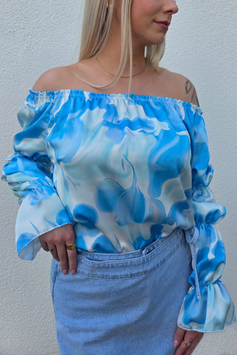 Elegante Off-Shoulder-Bluse aus fließendem Satin mit elastischem Ausschnitt für sicheren Sitz. Das seidig schimmernde Material zeigt ein verschwimmendes Wirbelmuster in Blau- und Weißtönen. Lange Ärmel mit Volant-Abschluss und leichtem Puff-Effekt verleihen der Bluse eine feminine Note. Der lockere Schnitt umspielt sanft die Figur und sorgt für ein luftiges Tragegefühl.