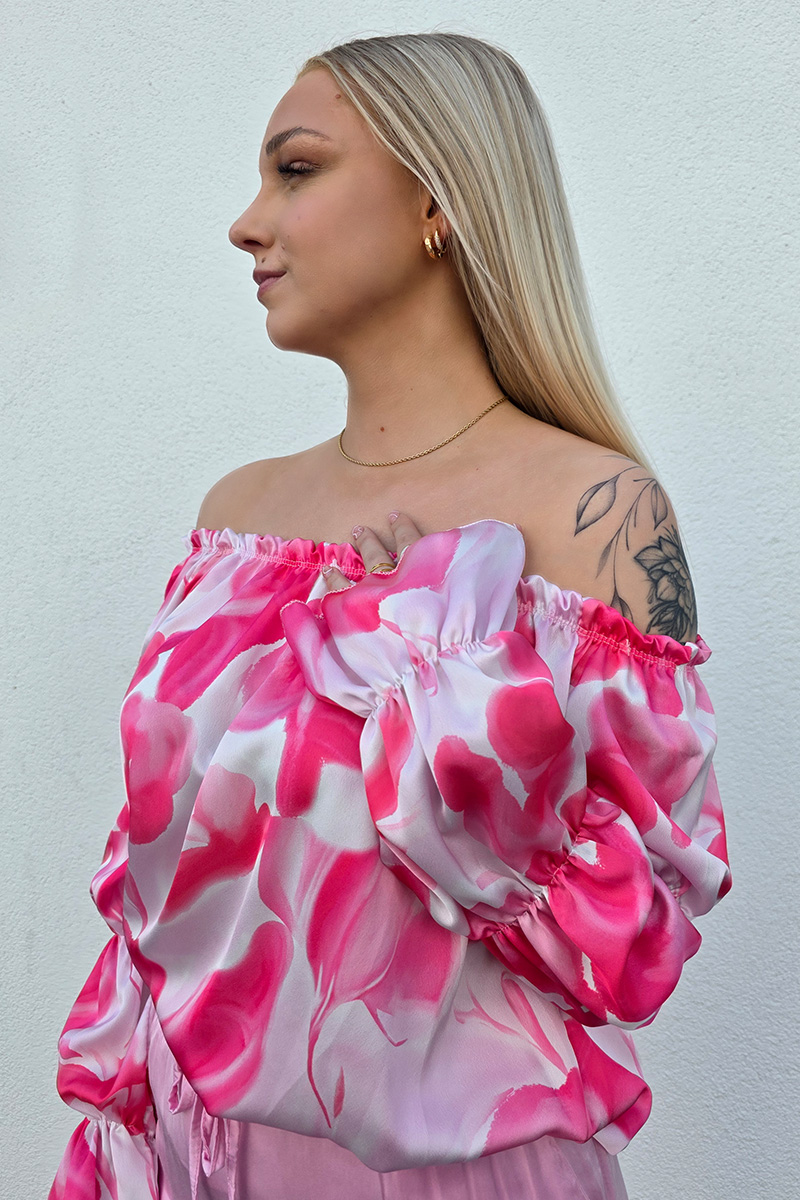 Elegante Off-Shoulder-Bluse aus fließendem Satin mit elastischem Ausschnitt für sicheren Sitz. Das seidig schimmernde Material zeigt ein verschwimmendes Wirbelmuster in Pink- und Weißtönen. Lange Ärmel mit Volant-Abschluss und leichtem Puff-Effekt verleihen der Bluse eine feminine Note. Der lockere Schnitt umspielt sanft die Figur und sorgt für ein luftiges Tragegefühl.