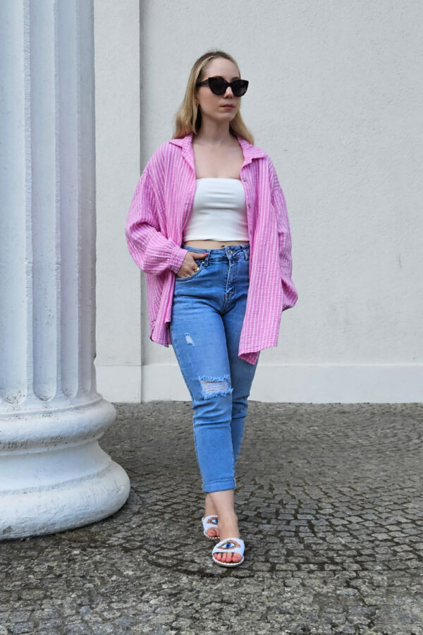 Gestreifte, lockere Bluse in rosa aus 100% Baumwolle, gefertigt aus weichem Musselinstoff. Die Bluse hat einen Oversize-Schnitt, der für einen lässigen Look sorgt. Sie besitzt einen V-Ausschnitt mit Umlegekragen und eine durchgehende Knopfleiste. Hinten ist eine querlaufende Falte eingearbeitet, die für zusätzliche Struktur sorgt. Die Bluse hat eine mittlere Länge und lange Ärmel mit 1-Knopf-Manschetten an den Ärmelenden.