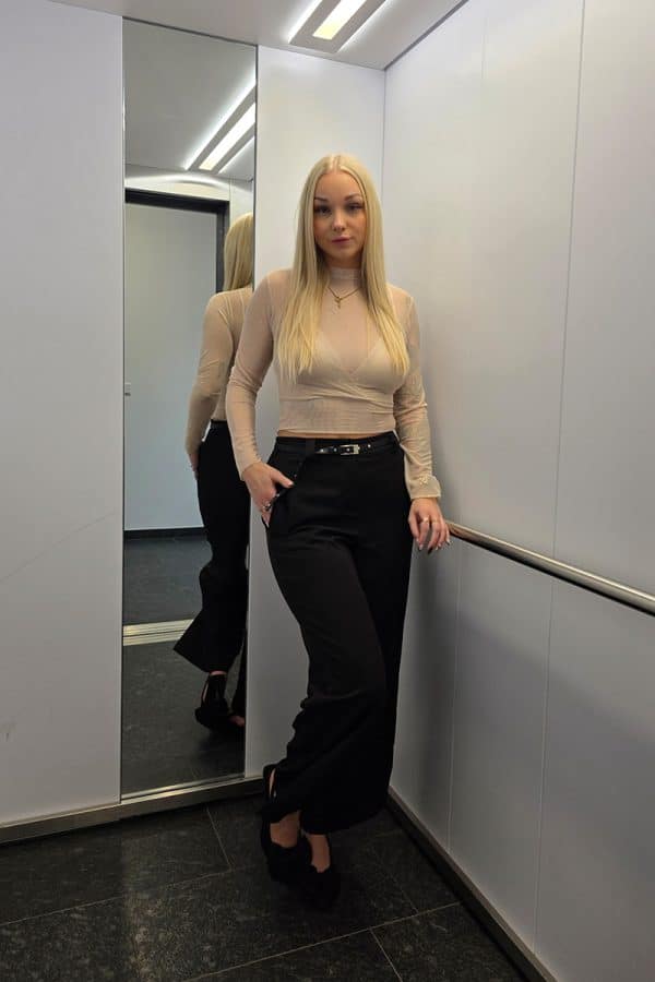 Nude-farbenes Mesh-Oberteil mit langen transparenten Ärmeln und feinen glitzernden Punkten. Unter dem durchsichtigen Tüll befindet sich ein integriertes, leicht gepolstertes Bralette-Crop-Top im gleichen Farbton. Das Oberteil wirkt feminin, leicht und elegant.