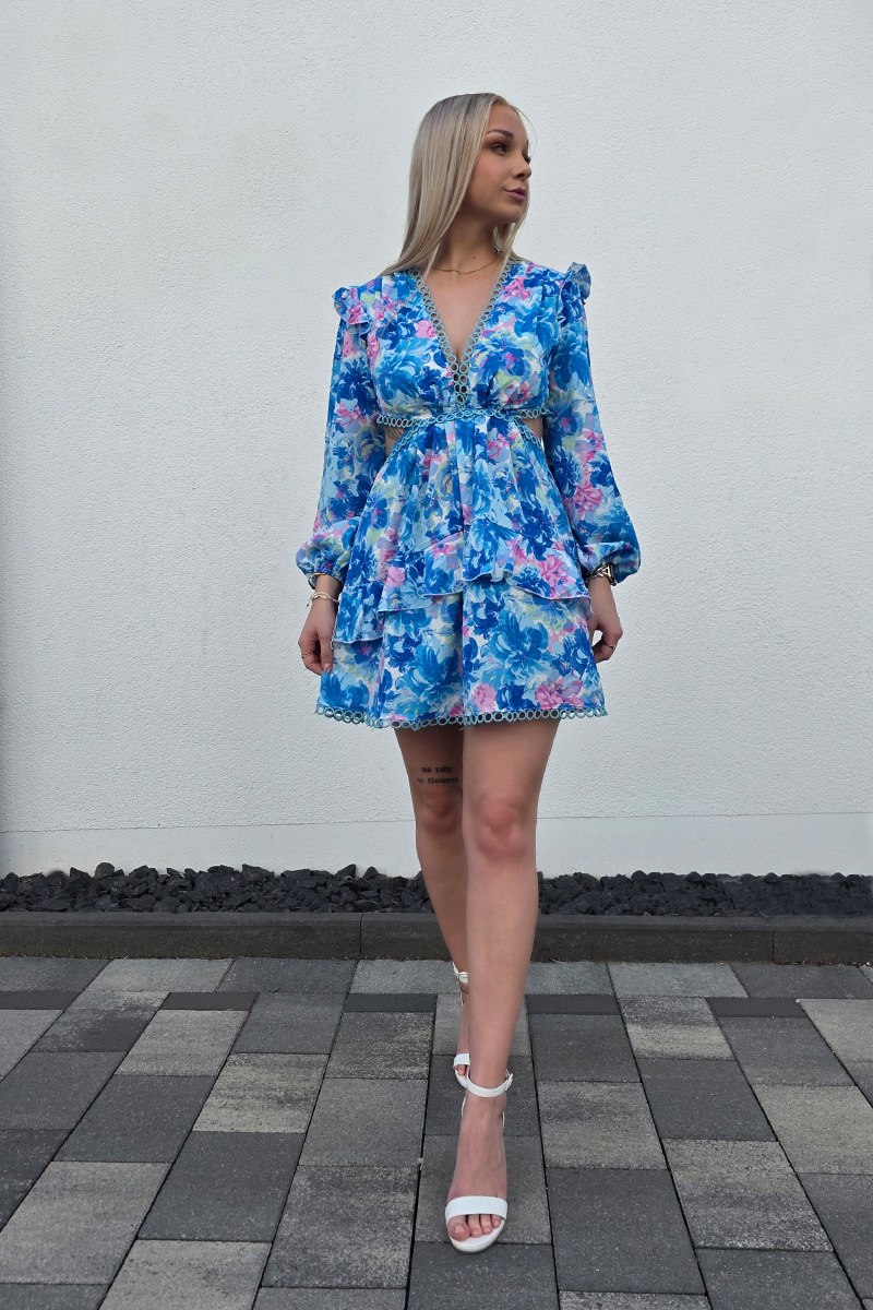 Sommerliches Minikleid mit floralem Muster in Blau- und Rosatönen, kurzem A-Linien-Rock und tiefem V-Ausschnitt für eine feminine Silhouette. Lange Puffärmel mit elastischen Bündchen sorgen für luftigen Tragekomfort. Seitliche Cut-outs und ein offener Rücken mit zarten gehäkelten Spitzeneinsätzen verleihen dem Kleid eine verspielte Boho-Note. Der stufige Volant-Rock und die kurze Passform machen das Kleid ideal für warme Tage und lässige Sommerlooks.
