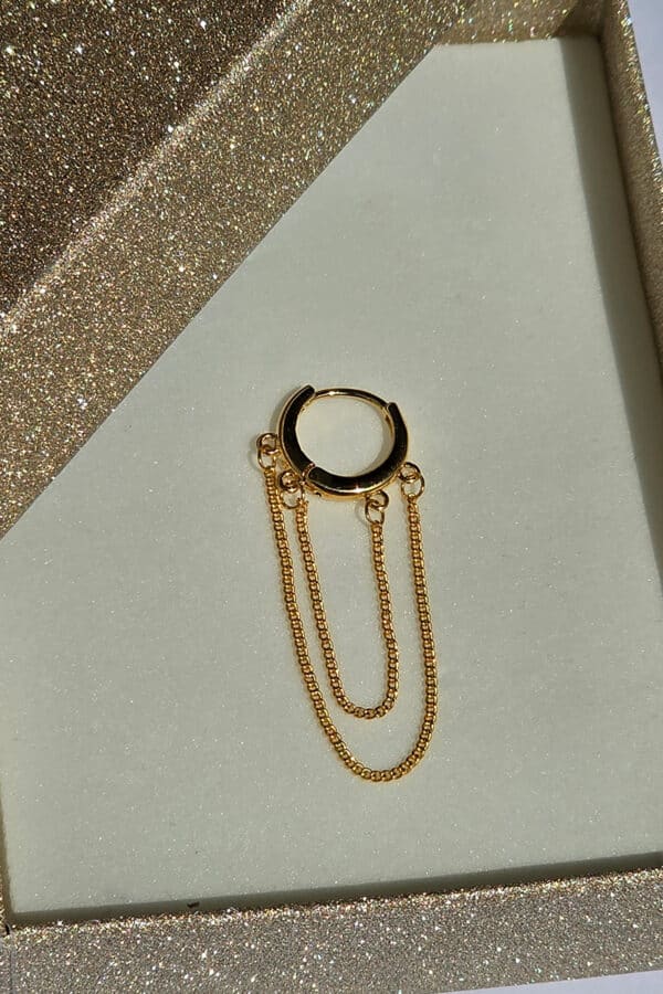 Elegante goldene Creolen mit stilvollem Kettenanhänger. Die Ohrringe verfügen über einen praktischen Klappringverschluss und sind aus Kupfer mit hochwertiger 14-Karat-Vergoldung gefertigt. Die glänzende Goldoptik verleiht ihnen einen modernen und zeitlosen Look. Rost- und nickelfreies Material sorgt für angenehmen Tragekomfort und macht die Creolen zum perfekten Accessoire für Alltag und besondere Anlässe.