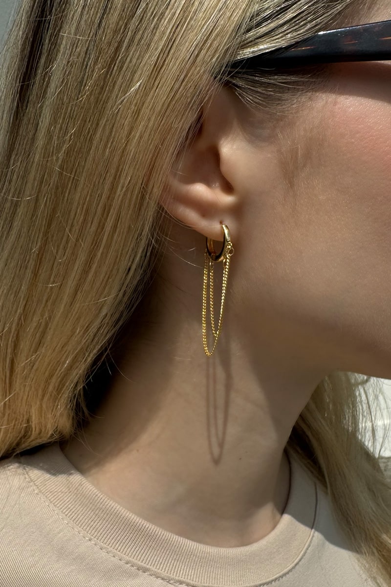 Elegante goldene Creolen mit stilvollem Kettenanh&auml;nger. Die Ohrringe verf&uuml;gen &uuml;ber einen praktischen Klappringverschluss und sind aus Kupfer mit hochwertiger 14-Karat-Vergoldung gefertigt. Die gl&auml;nzende Goldoptik verleiht ihnen einen modernen und zeitlosen Look. Rost- und nickelfreies Material sorgt f&uuml;r angenehmen Tragekomfort und macht die Creolen zum perfekten Accessoire f&uuml;r Alltag und besondere Anl&auml;sse.