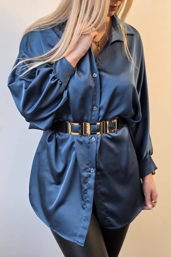 Dunkelblaue Oversize Damenbluse aus weich fließendem, leicht glänzendem Stoff. Die Bluse hat lange Fledermausärmel, eine klassische Knopfleiste vorne und einen dezenten Stehkragen. Der verlängerte, abgerundete Saum am Rücken sorgt für einen modernen, eleganten Look. Ideal für Büro, Alltag oder festliche Anlässe, mit lockerer Passform für maximalen Tragekomfort.