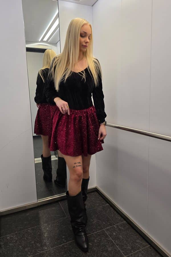 Weinroter Paillettenrock aus weichem Samt für Damen, mit intensiv funkelnder Glitzeroberfläche und elastischem Bund. Festlicher Minirock im A-Linien-Schnitt, ideal als Partyrock, Glitzerrock oder eleganter Rock für besondere Anlässe. Der Rock besitzt eingenähte Shorts für Sichtschutz und maximalen Tragekomfort.