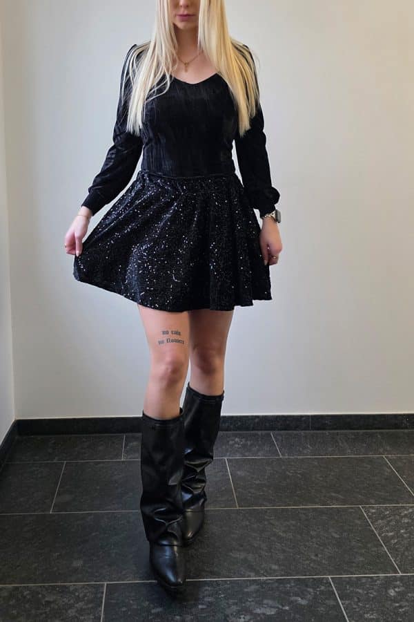 Schwarzer Paillettenrock aus weichem Samt für Damen, mit intensiv funkelnder Glitzeroberfläche und elastischem Bund. Festlicher Minirock im A-Linien-Schnitt, ideal als Partyrock, Glitzerrock oder eleganter Rock für besondere Anlässe. Der Rock besitzt eingenähte Shorts für Sichtschutz und maximalen Tragekomfort.