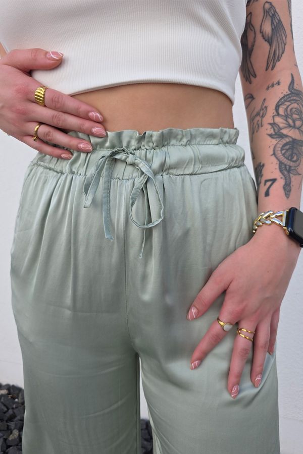 Diese edle Hose in Satin-Optik in einem eleganten Olivton überzeugt mit einem hohen, elastischen Paperbag-Bund und einem lockeren, weiten Schnitt, der luftig und bequem sitzt. Seitliche Eingrifftaschen sorgen für praktische Details, während das fließende Material einen femininen Look unterstreicht. Ideal kombinierbar mit einem Bandeau-Top und Sandaletten für einen lässig-eleganten Casual Chic Style.