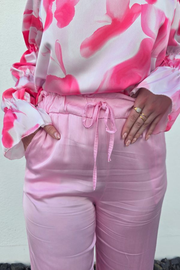 Diese edle Hose in Satin-Optik in einem eleganten Rosaton überzeugt mit einem hohen, elastischen Paperbag-Bund und einem lockeren, weiten Schnitt, der luftig und bequem sitzt. Seitliche Eingrifftaschen sorgen für praktische Details, während das fließende Material einen femininen Look unterstreicht. Ideal kombinierbar mit einem Bandeau-Top und Sandaletten für einen lässig-eleganten Casual Chic Style.