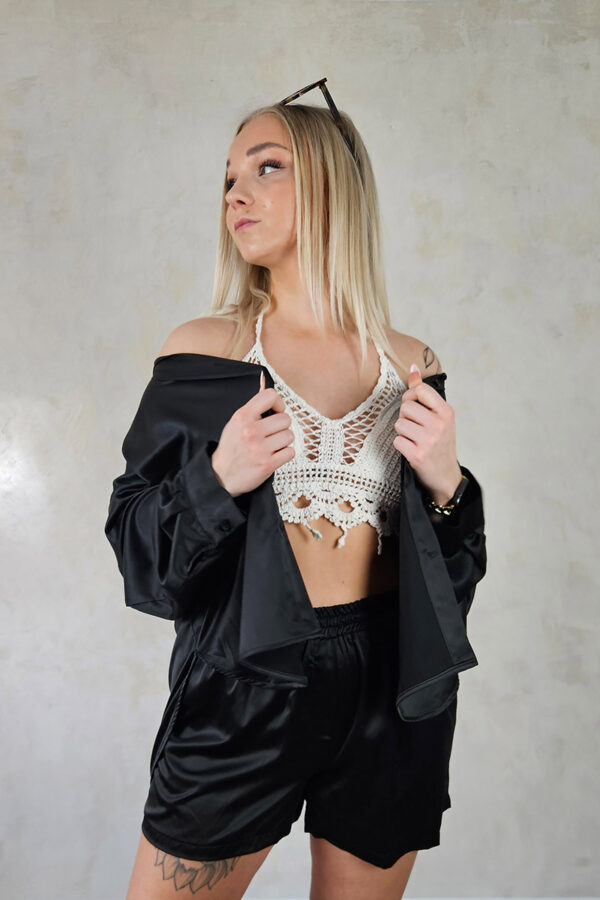 Eine glänzende Satinshorts in schwarz mit einem elastischen Bund für Tragekomfort. Die Shorts haben seitliche Taschen und eine angenähte Reißverschlussblende. Perfekt kombinierbar mit einer passenden Satinsbluse für ein harmonisches und stilvolles Outfit.