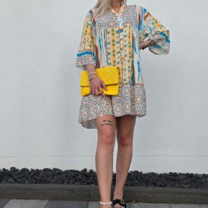 Dieses leichte Boho Kleid mit Knopfleiste ist aus luftigem, fließendem Stoff gefertigt und mit einem auffälligen Ethno-Muster in Blau, Braun und Gelb verziert. Der kurze, lockere Schnitt in knieumspielender Länge sorgt für Bewegungsfreiheit, während der V-Ausschnitt und die 3/4-Ärmel mit leichtem Puff-Effekt dem Kleid eine feminine und sommerliche Note verleihen.