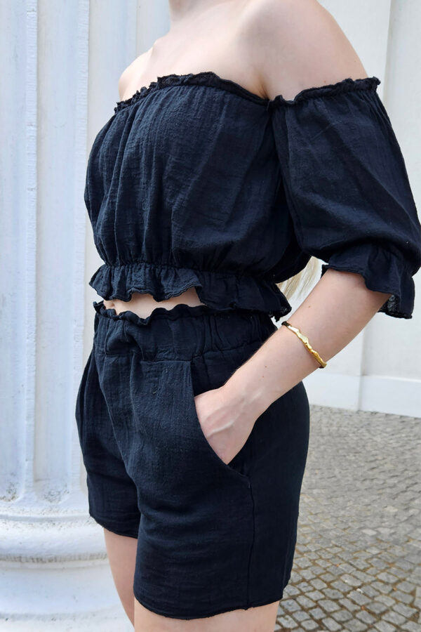 Das Sweet Summer Delights Se in schwarzt aus luftigem Baumwollstoff. Das Set besteht aus einem Off-Shoulder Crop Top mit elastischem Saum und Rüschen sowie ¾ Puffärmeln. Dazu gehören High Waist Shorts mit Seitentaschen und einem elastischen Bund, die für eine bequeme Passform sorgen.