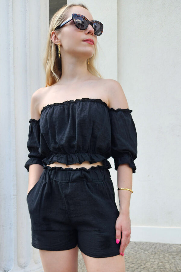 Das Sweet Summer Delights Se in schwarzt aus luftigem Baumwollstoff. Das Set besteht aus einem Off-Shoulder Crop Top mit elastischem Saum und Rüschen sowie ¾ Puffärmeln. Dazu gehören High Waist Shorts mit Seitentaschen und einem elastischen Bund, die für eine bequeme Passform sorgen.