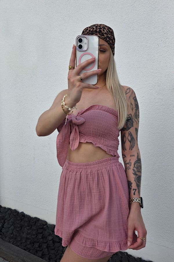 Zweiteiler-Set aus weichem Musselin in Altrosa, bestehend aus einem bauchfreien, gesmockten Bandeau-Top mit Bindeband und einem High-Waist Minirock mit elastischem Bund. Der Rock ist mit eingenähten Shorts unterlegt und mit verspielten Rüschen-Säumen verziert – ideal für luftige Sommer-Looks.