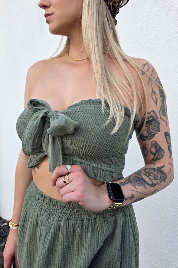 Zweiteiler-Set aus weichem Musselin in khaki, bestehend aus einem bauchfreien, gesmockten Bandeau-Top mit Bindeband und einem High-Waist Minirock mit elastischem Bund. Der Rock ist mit eingenähten Shorts unterlegt und mit verspielten Rüschen-Säumen verziert – ideal für luftige Sommer-Looks.