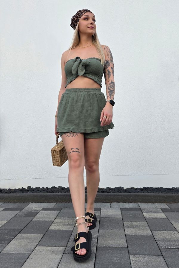 Zweiteiler-Set aus weichem Musselin in khaki, bestehend aus einem bauchfreien, gesmockten Bandeau-Top mit Bindeband und einem High-Waist Minirock mit elastischem Bund. Der Rock ist mit eingenähten Shorts unterlegt und mit verspielten Rüschen-Säumen verziert – ideal für luftige Sommer-Looks.